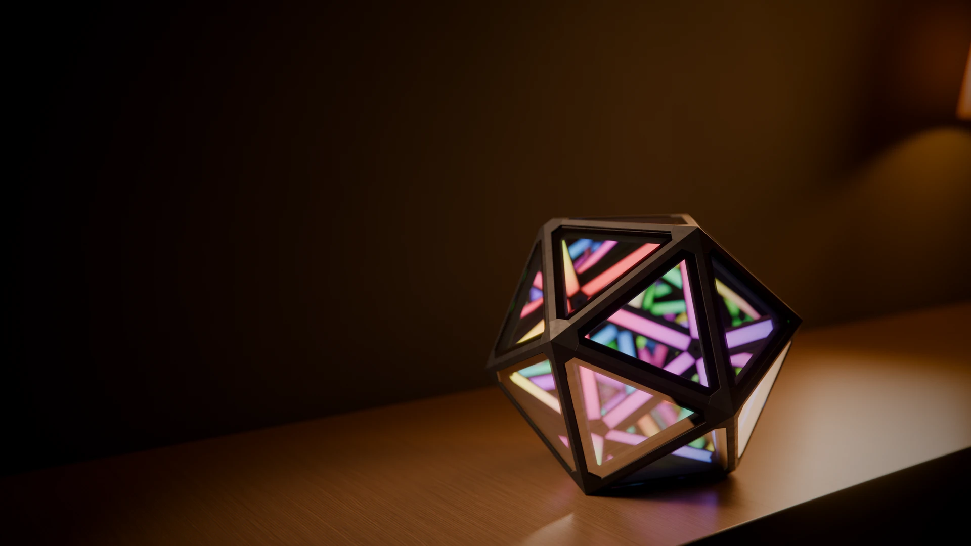 The Infinity Icosahedron lamp glowing in a dark room, its mirrored faces holding tunnels of light.